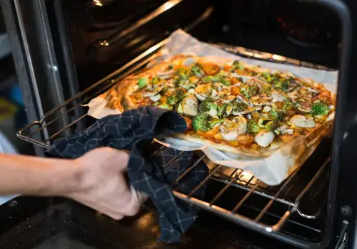 Pessoa assando pizza no forno elétrico