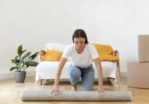 Mulher desenrolando um tapete para a sala